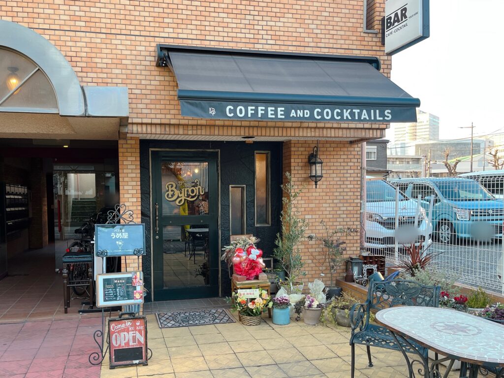 店舗外観。茶色タイル造りの建物に深緑色のドア。