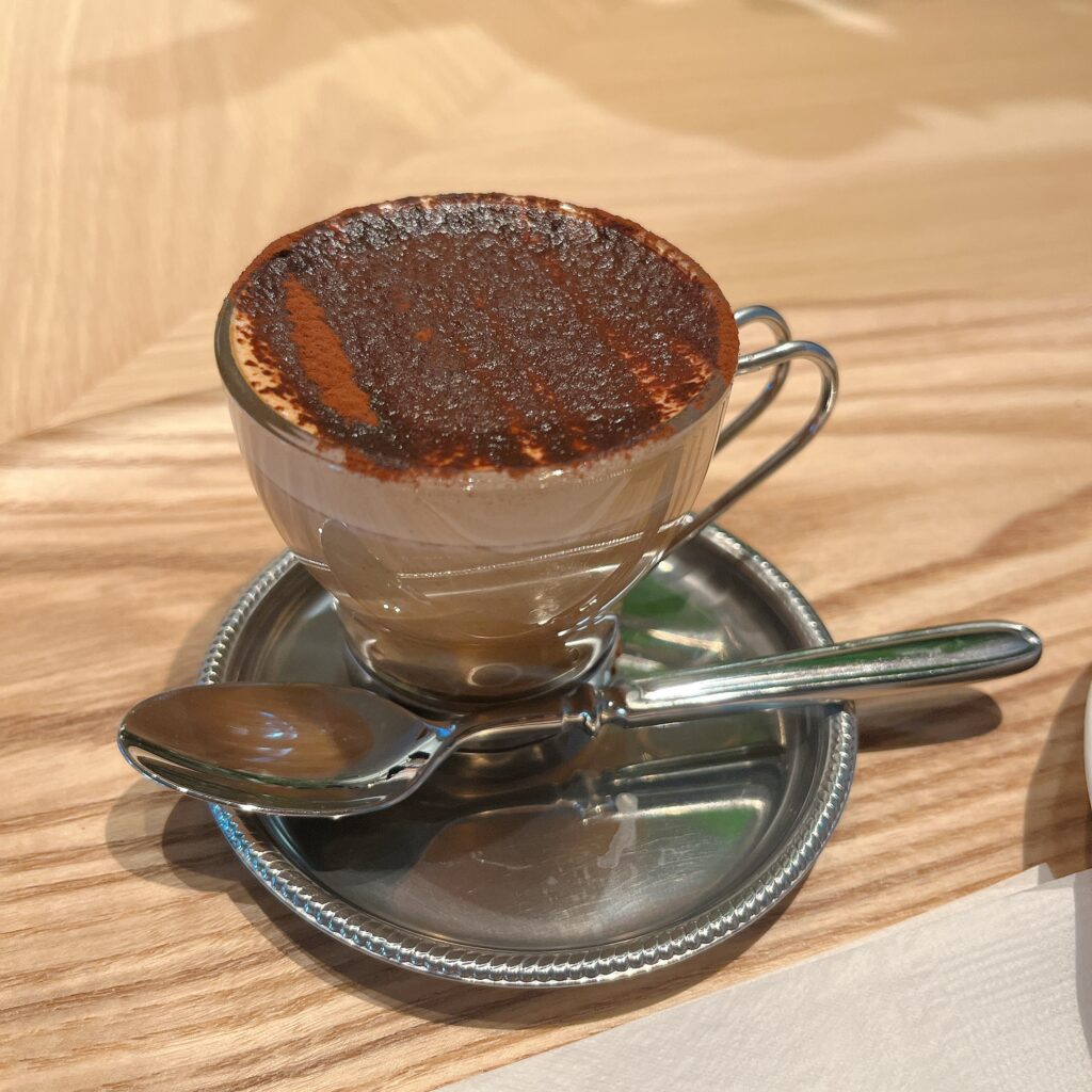 透明なカップに入ったコーヒードリンク。上にココアパウダーが乗っている