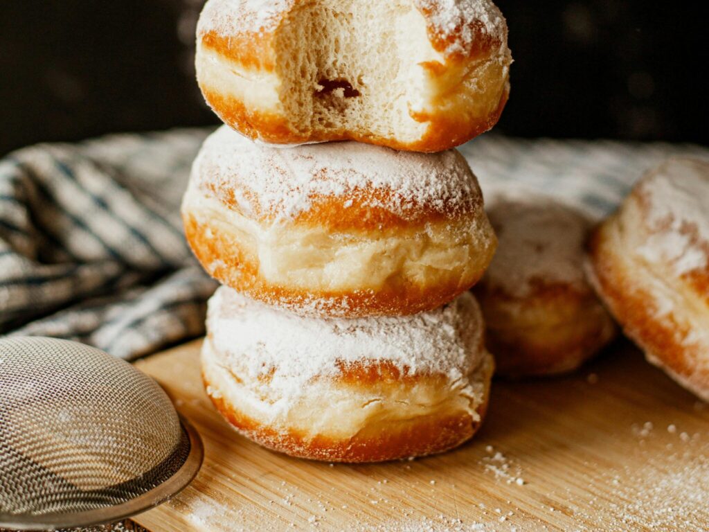 クッキングボードの上に丸い穴の開いていないドーナツが積み重なっている写真