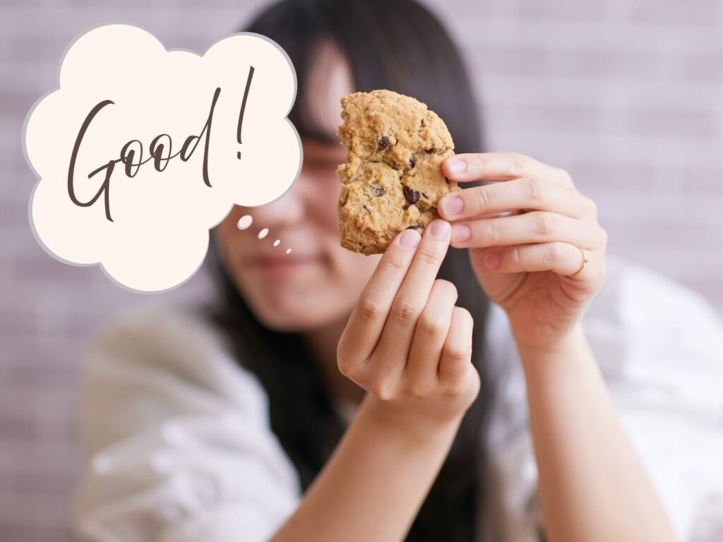 クッキーを持っている女性が「グッド」と言っている写真
