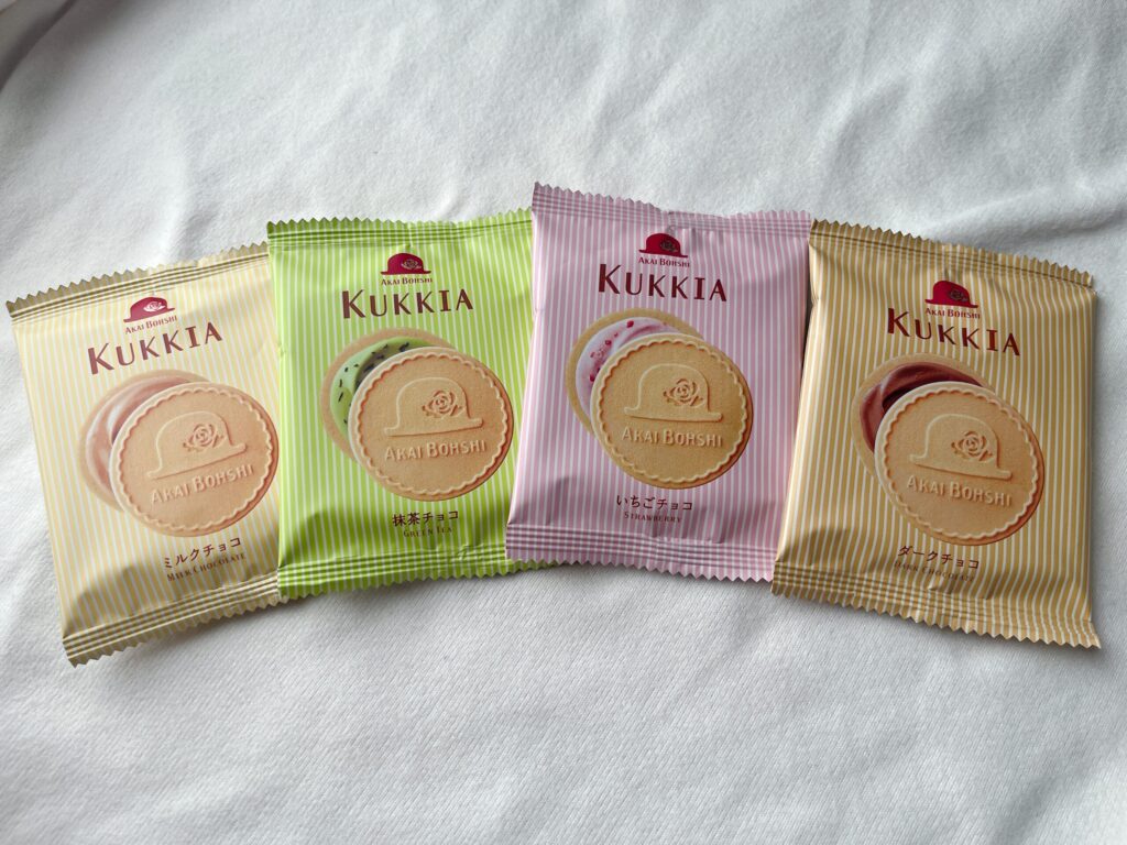 左から黄色、緑、ピンク、茶色の小袋に入った「クッキア」が並んでいる。