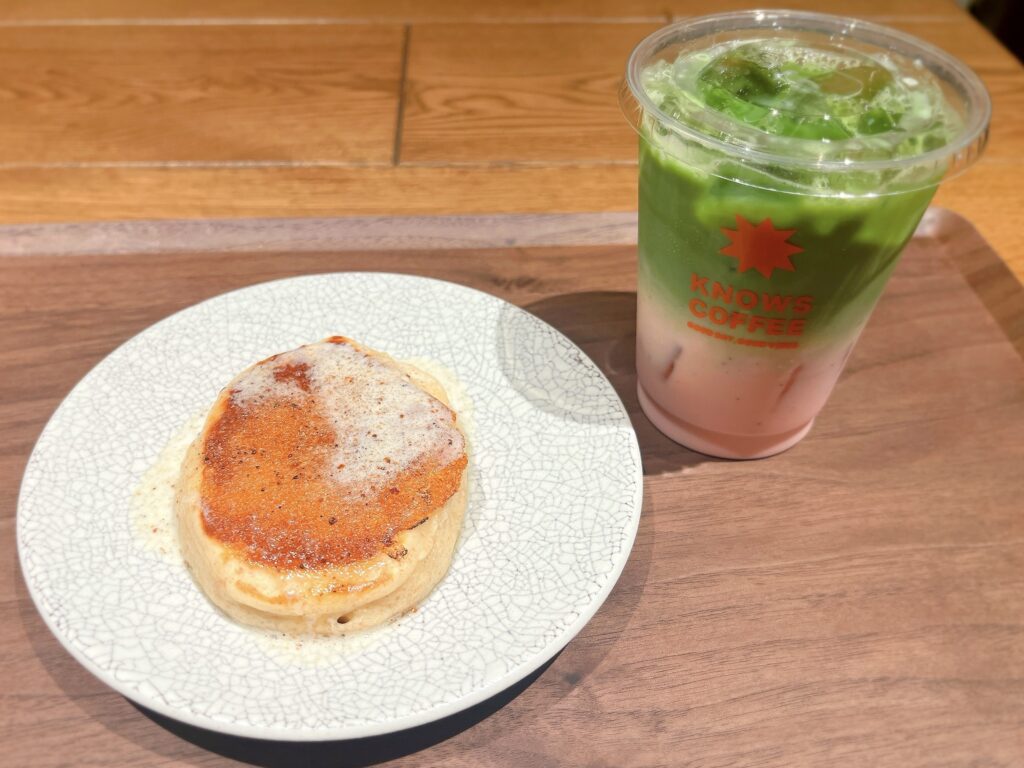 パンケーキの上にトリュフバターがじゅわっと溶け出している。横にはいちご抹茶ラテ。下側がピンク、上側が緑色のグラデーションになっている。