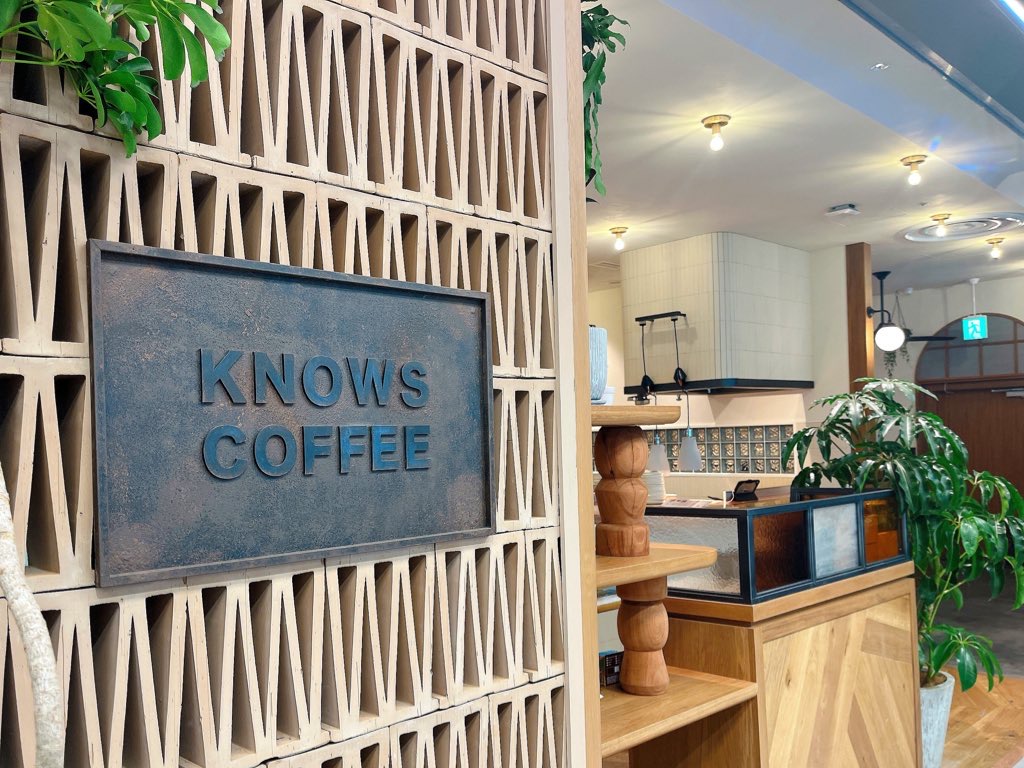 店舗入り口。木製のデザインウォールに石板風の店名が書かれたプレートがある。