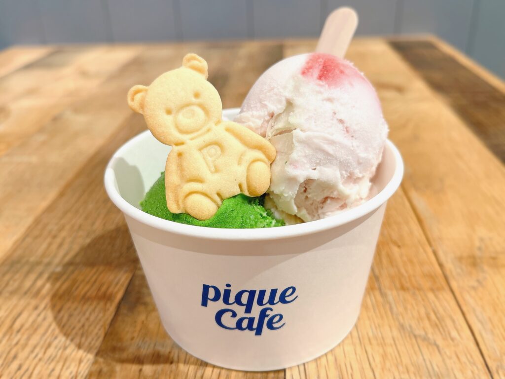 カップに抹茶といちごのフレーバーのジェラートが入っている。抹茶ジェラートの上にはテディベアの形のクッキーが乗っている。