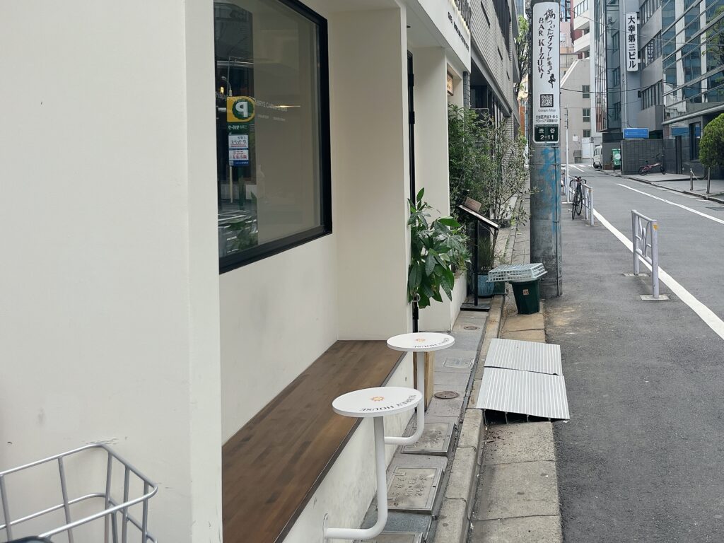 店外のテラス席。木製のベンチの横に小さな丸いテーブルが設置されている。