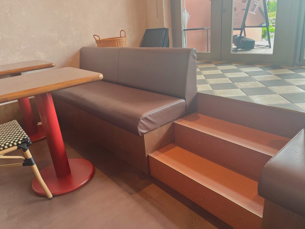 木製テーブルの脚が赤色だったり、タイルが白黒のおしゃれな店内の写真