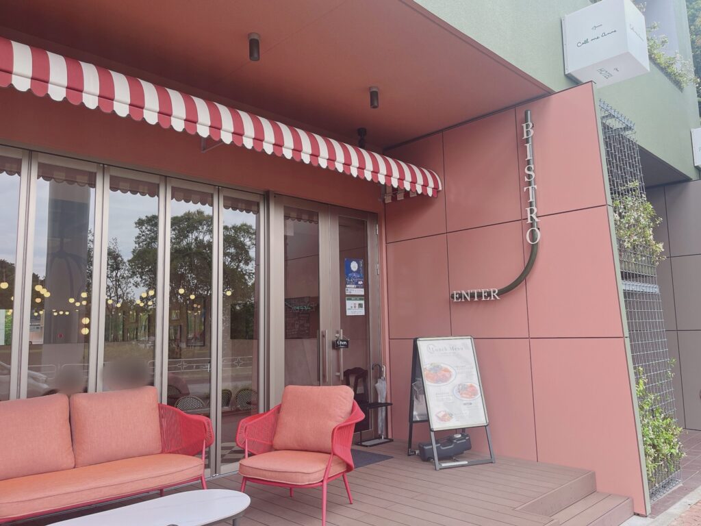 ピンクと黄緑色のおしゃれなカラーリングの壁面に、赤と白のインテリアが置かれた店舗外観。