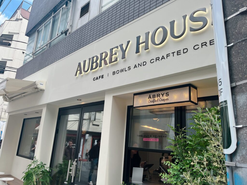 白い壁に黒い文字で店名が書かれている、店舗外観の写真。