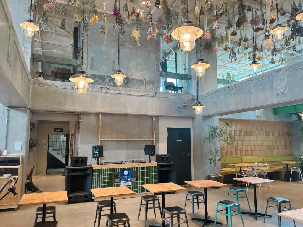 打ちっぱなしコンクリートの建物内、天井からはドライフラワーが吊るされ、下にはDJブースがある写真