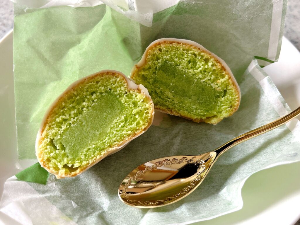 本品の断面。中心に緑色のずんだ餡があり、その周りをずんだのスポンジケーキ、最後にホワイトチョココーティング、という重なり具合。